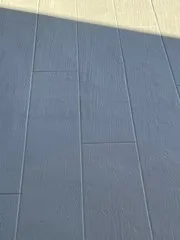 Downward close-up of gray rectangular deck panels crossed by a broad shadow