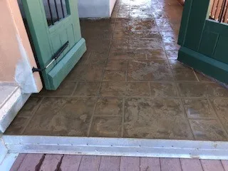 Doorway view of wet brown patterned deck between open green double doors