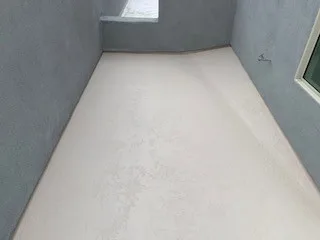 Elevated view of smooth white coated balcony enclosed by gray parapet walls