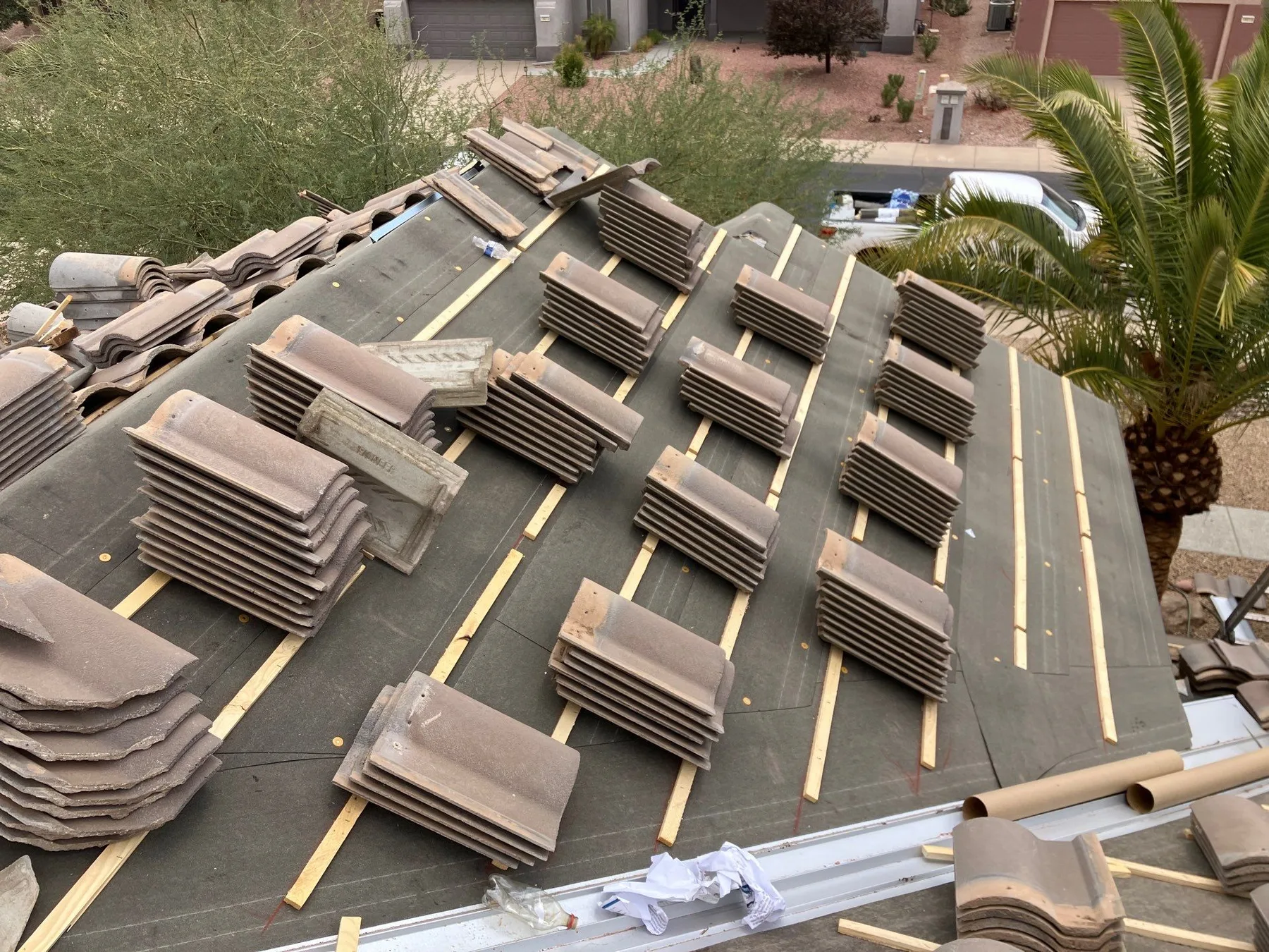 Aerial view of sloped roof installation with dark underlayment, battens, and stacked tiles