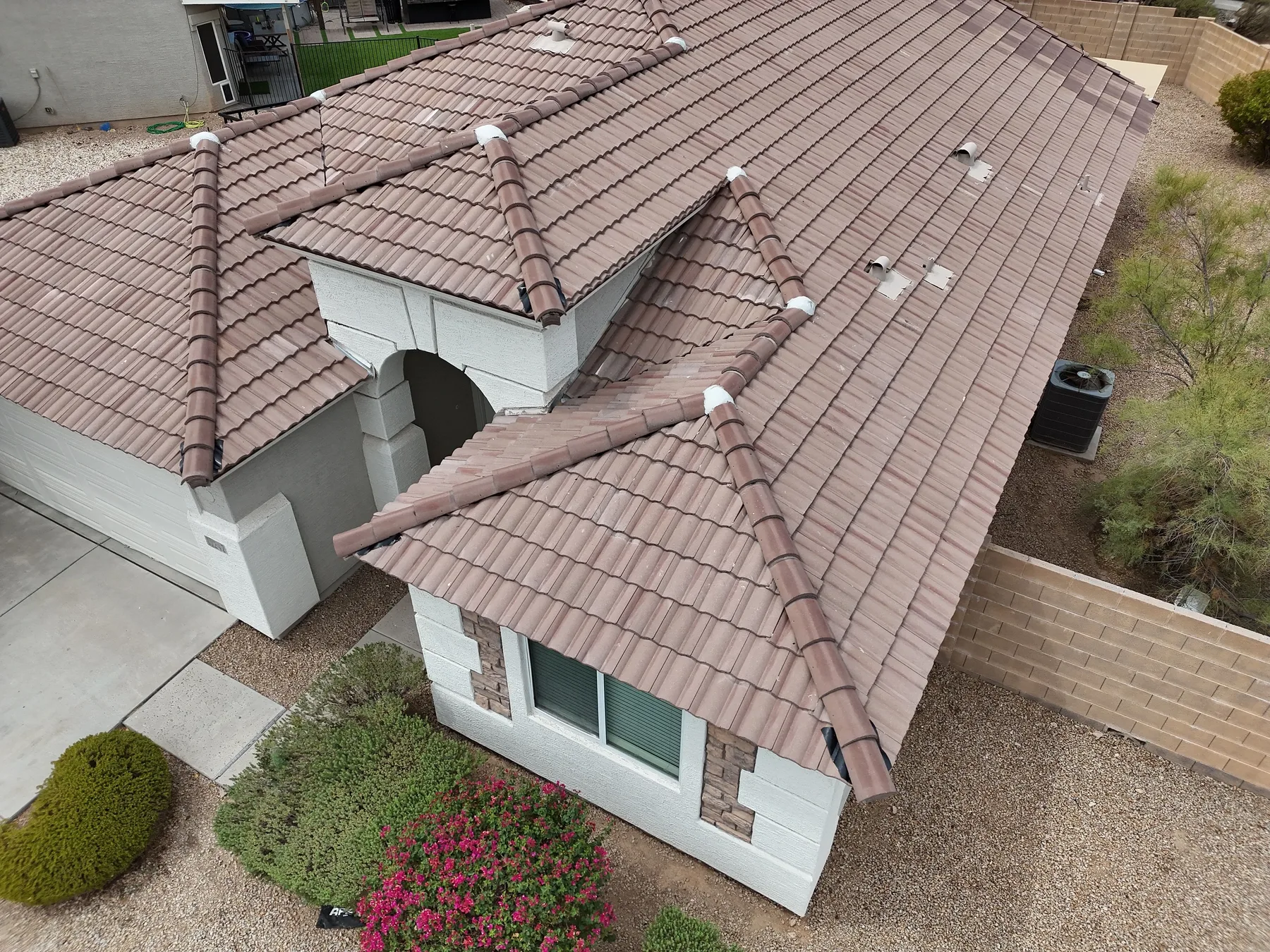Aerial view of completed rose-brown tile hip roof with ridges, vents, and entry arch