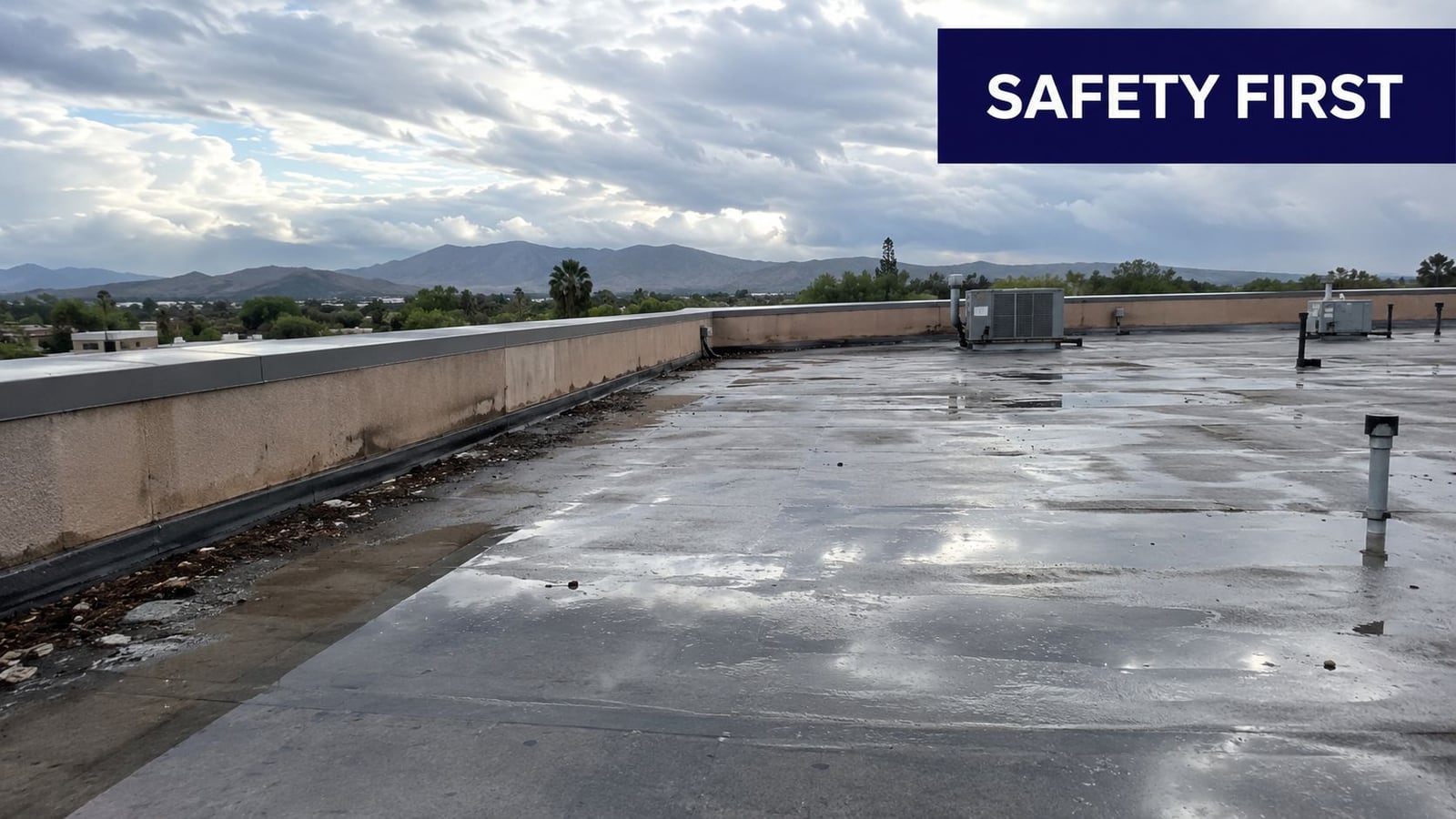 A wet, flat commercial rooftop after a rainstorm with distant mountains under a cloudy sky.