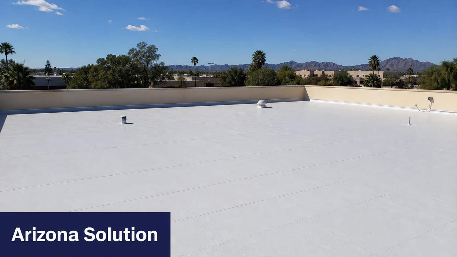 A commercial flat roof in Arizona featuring a smooth, newly applied white waterproof coating under clear skies.
