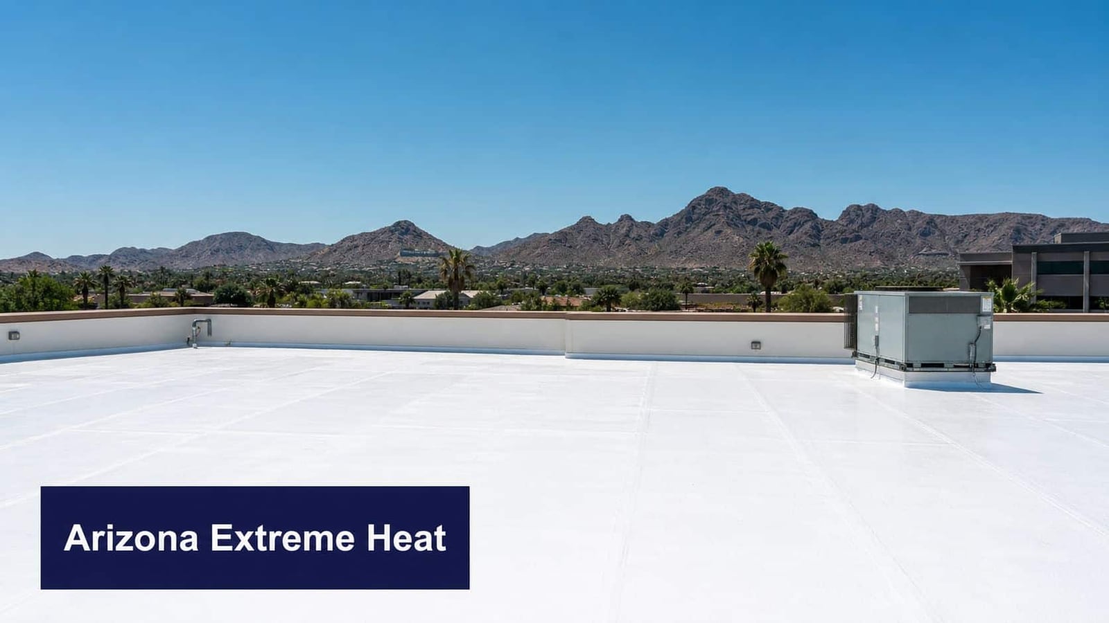 A bright white commercial low slope roof overlooking a desert landscape with mountains under a clear sky.